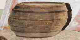 A tall, narrow wooden barrel with a bung hole and metal hoops holding its staves together.