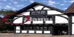 A Tudor-style house with arching timber braces in its corners.