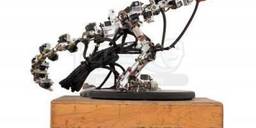 a small metal T-Rex skeleton with wires, perched on a wooden crate labeled Phil Tippet Co.